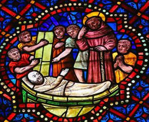 Fototapeta premium Stained Glass of a dying man and a Catholic Saint in Cathedral o