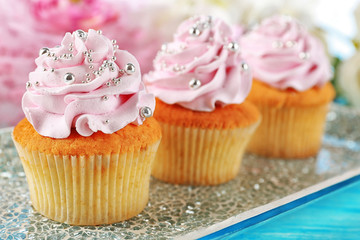Tasty cupcakes on plate, on color wooden background