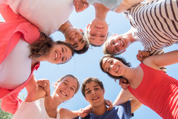 Under view of seven trendy teenagers arm in arm. 