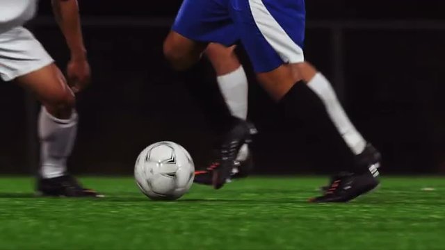 Close up of soccer players kicking a ball down the field
