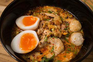 bowl of noodles with vegetables and soft boiled egg on wooden ta