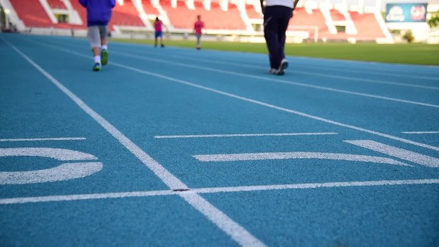 Slow motion, young Asian boy runing in blue running track.