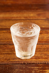 glass of clear alcohol on wooden table