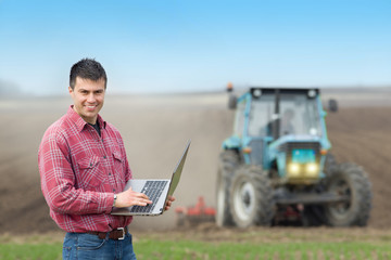 Naklejka na ściany i meble Farmer with laptop in the field