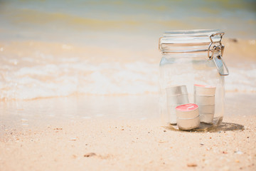Fototapeta na wymiar Candles in jar with beautiful beach and sea in background - vint