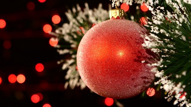 Unusual decoration - a round red toy on christmas tree, bokeh, light, black, garland