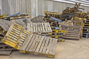 Old Stacked wooden pallets are lumber near a factory.
dilapidated wood pallets background.