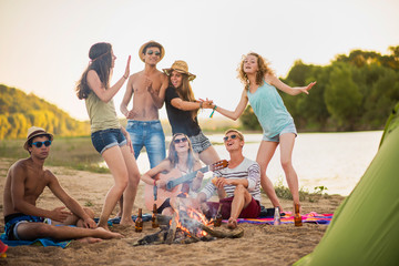 Teenagers having fun at the beach. They are singing and dancing