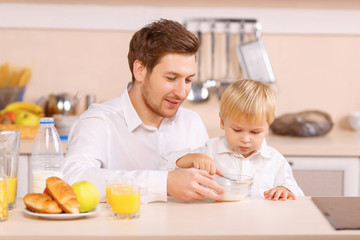 Obraz na płótnie Canvas Daddy helps his son to finish a cereal.
