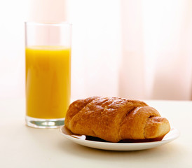 Glass of juice and croissant on a plate