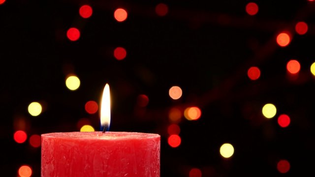 Top of two red candles with christmas decorations on black, bokeh, light, garland