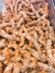 Heaps of freshly harvested turmeric roots in supermarket