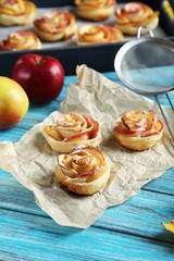 Fresh puff pastry with apple shaped roses on blue wooden table