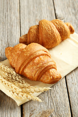 Tasty croissants with spikelets on grey wooden background