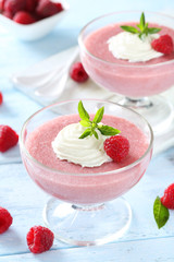 Sweet raspberry mousse in glass on blue wooden table