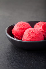 Cherry, raspberry, strawberry, cranberry , red sorbet,scoop, black stone background. 