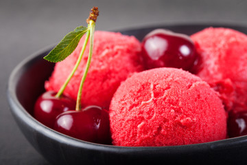 Cherry, raspberry, strawberry, cranberry , red sorbet,scoop, black stone background. 