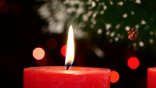 Two red candles with christmas decorations on black, bokeh, light, garland, cam moves to the right
