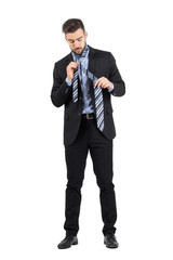 Obraz premium Young bearded business man getting dressed. Full body length portrait isolated over white studio background. 