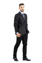 Serious confident bearded businessman holding document folder walking while looking at camera. Full body length portrait isolated over white studio background. 