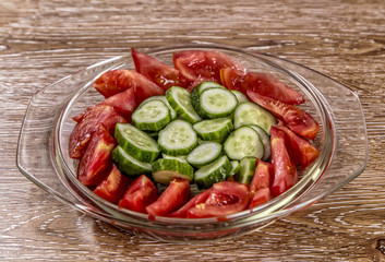 Tomato and cucumber  salad on the glass bowl on wooden background