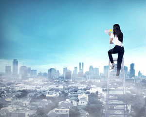 Business woman standing on the ladder high and shout with megaphone