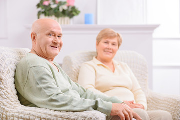 Loving adult couple sitting in arm chairs 