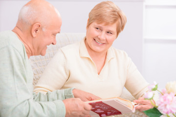 Pleasant couple looking through photo album 