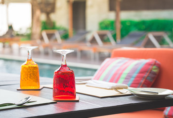 Red and Yellow Glass of water on luxury table setting near swimm