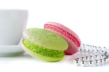 Green and pink macaroons with a cup and silver chaplet