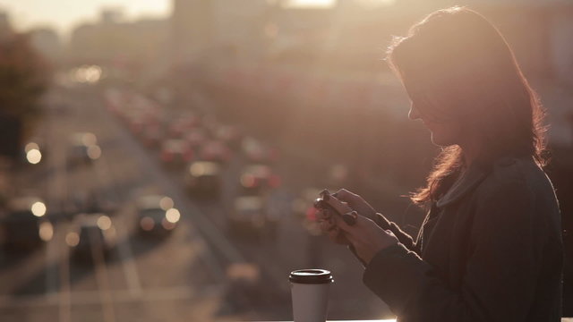 beautiful girl uses a smartphone on a city bridge 