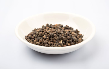 Black peppercorn in white bowl over white background