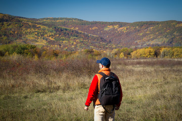 Male tourist with backpack sotret on the horizon in autumn