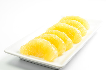 Fresh peeled pomelo citrus fruit on white dish
