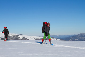 Winter hiking in the mountains on snowshoes with a backpack and tent.