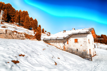 High-altitude mountain hut among snow-capped peaks and pine fore