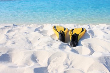 Obraz premium Bright fins on beach prepared for snorkeling, turquoise sea and white sand coast. Tropical island. Empty vacation at seaside background.