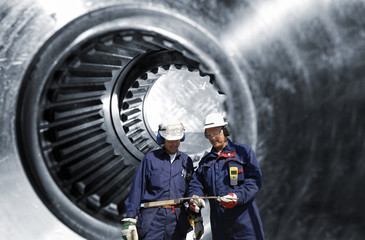 steel workers, engineers with large cogwheels,  gear axle in background