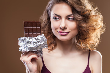 Portrait of a chocolate loving young brunette beauty over brown background