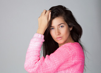 Young beautiful tempting brunette woman in pink pullover poses and smile.