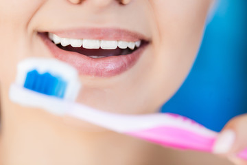 Beautiful smiling woman holding a toothbrush and toothpaste, fresh studio portrait