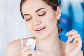 Young woman cleaning her teeth with dental floss