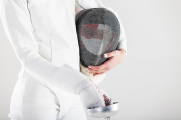 Portrait of woman wearing white fencing costume practicing with the sword