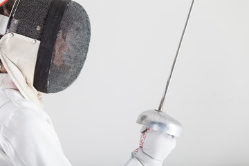 Portrait of woman wearing white fencing costume practicing with the sword