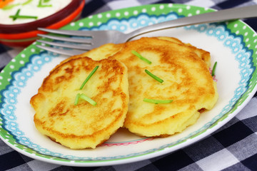 Golden potato fritters garnished with spring onions, closeup
