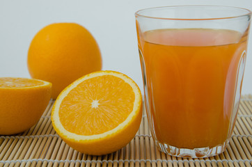 Orange Juice and Sliced Organic Orange On Bamboo Mat.