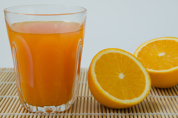 Orange Juice and Sliced Organic Orange On Bamboo Mat.