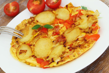 Omelette with potatoes, onions, red pepper and sweetcorn on white plate, closeup
