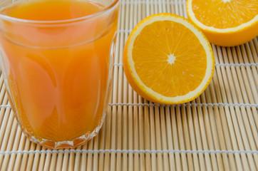 Orange Juice and Sliced Organic Orange On Bamboo Mat.