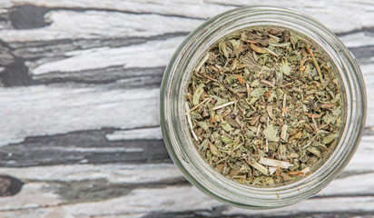 Dried lemon balm leaves in mason jar over wooden background